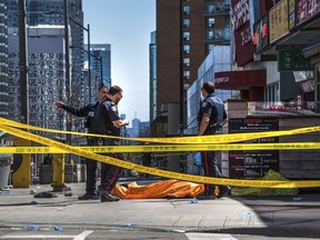 Police officers stand by a covered body in Toronto after a van mounted a sidewalk and crashed into a crowd of pedestrians on Monday, April 23, 2018. The van apparently jumped a curb Monday in a busy intersection in Toronto, struck the pedestrians and fled the scene before it was found and the driver was taken into custody, Canadian police said.