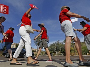 Arizona teachers protest their low pay and school funding in front of a local radio station waiting for Republican Gov. Doug Ducey to show up for a live broadcast Tuesday, April 10, 2018, in Phoenix. Arizona teachers are threatening a statewide walkout, following the lead of educators in other states.