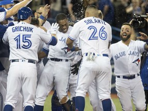 Curtis Granderson is mobbed by Blue Jays teammates after he hit a walkoff home run in the 10th inning to beat the Boston Red Sox 4-3 at Rogers Centre in Toronto on Tuesday night.