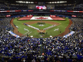 Fans stand for the national anthems before the Toronto Blue Jays' home opener on March 29.
