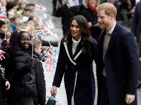In this Thursday, March 8, 2018 file photo, Britain's Prince Harry and his fiance Meghan Markle are greeted by flag waving school children as they arrive to take part in an event for young women as part of International Women's Day in Birmingham, central England. Kensington Palace says the California-born Markle intends to take U.K. citizenship after she marries Harry on May 19 at Windsor Castle.
