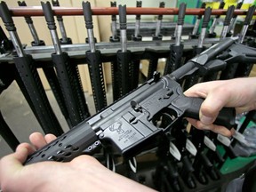 FILE - In this April 10, 2013 file photo, craftsman Veetek Witkowski holds a newly assembled AR-15 rifle at the Stag Arms company in New Britain, Conn. A ruling released Friday, April 6, 2018, by a federal judge in Boston, dismissed a lawsuit challenging Massachusetts' ban on assault weapons and large-capacity magazines, stating that assault weapons are beyond the scope of the Second Amendment right to "bear arms."