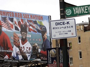 FILE - In this April 10, 2007 file photo, a Yawkey Way street sign hangs on a pole outside Fenway Park before a baseball game between the Boston Red Sox and Seattle Mariners in Boston. The City of Boston approved a plan Thursday, April 26, 2018, to change the name of Yawkey Way to Jersey Street, it's original name. The street had been named in honor of former Red Sox owner Tom Yawkey, who some have said was racist.