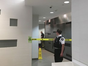 A security guard stands by as fire fighters inspect a wall in the women's washroom in the Core Shopping Centre in Calgary on Monday, April 30, 2018. Calgary police are investigating after a body was found in a wall in a downtown mall bathroom.