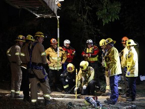Firefighters search for a 13-year-old boy in a hole near the LA River at the 134 and 5 Freeway interchange Sunday, April 1, 2018, in Los Angeles. The  13-year-old boy, who fell into a drainage pipe during a family Easter outing at a Los Angeles park, was found alive early Monday following a frantic, 12-hour search of the underground system, authorities said.
