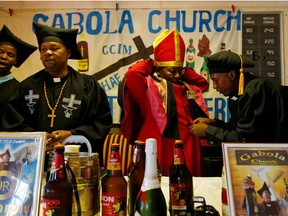 Leader of the Gabola Church, self-proclaimed Pope Tsietsi Makiti, second from right, prepares for a service in a bar in Orange Farm, south of Johannesburg Sunday, April 15, 2018. The new church in South Africa celebrates drinking alcohol and holds enthusiastic, alcohol fuelled services in bars, for those who have been rejected by other churches because they drink alcohol.