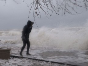A woman walks along the boardwalk on Toronto's waterfront as a the city is hit by a storm on Sunday, April 15, 2018.