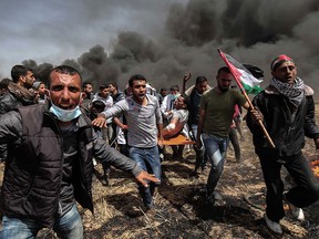 An injured Palestinian protestor is carried by fellow demonstrators during clashes with Israeli security forces near the border with Israel, east of Khan Yunis, in the southern Gaza Strip, on Friday, April 6, 2018.