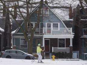 A man cross country skis past houses on the edge of Trinity Bellwoods Park in Toronto, Ontario as a mix of snow, hail, and rain fall on Sunday, April 15. 2018.