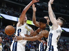 Milwaukee Bucks forward Giannis Antetokounmpo passes the ball as Denver Nuggets center Nikola Jokic, left, and forwards Trey Lyles and Juan Hernangomez, right, defend during the first half of an NBA basketball game Sunday, April 1, 2018, in Denver.