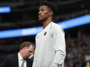 Injured Minnesota Timberwolves guard Jimmy Butler watches during the first half of the team's NBA basketball game against the Denver Nuggets on Thursday, April 5, 2018, in Denver.