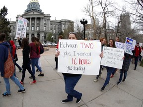 Rita Pereira, a teacher in the Jefferson County, Colo., school system, holds a placard as she joins fellow teachers in marching around the State Capitol during a rally Thursday, April 26, 2018, in Denver. More than 10,000 teachers in Colorado are expected to demonstrate as part of a burgeoning teacher uprising from the East to the interior West that is demanding more tax dollars be spent in public schools.