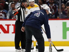 A crew member picks up a catfish tossed on the ice as Nashville Predators left wing Viktor Arvidsson, back, looks on in the second period of Game 3 of an NHL hockey first-round playoff series against the Colorado Avalanche Monday, April 16, 2018, in Denver.