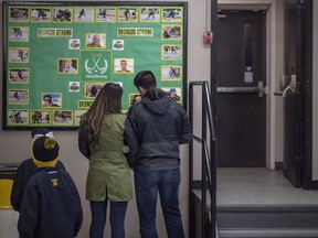 People look at a memorial wall for the Humboldt Broncos in the lobby during game one of the Saskatchewan Junior Hockey league finals between the Estevan Bruins and Nipawin Hawks in Nipawin, Sask., on April 14, 2018. Some families of Humboldt Broncos bus crash victims are surprised to learn that error-riddled obituaries of their loved ones have been posted on a website that's selling flowers, as well as online memorial candles, and that the site isn't donating the money.Eleven of the 16 people who died when the Saskatchewan Junior B hockey team's bus collided with a semi on April 6 are listed on the Everhere website, which calls itself one of North America's largest databases for obituaries.