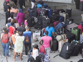 Asylum seekers line up to enter Olympic Stadium Friday, August 4, 2017 near Montreal, Quebec. Canadian border officials are preparing for another expected spike in asylum seekers coming illegally into the country through Quebec and Ontario from the U.S. as the weather gets warmer.