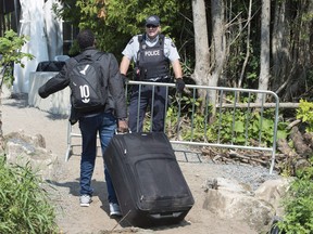 An asylum seekers, claiming to be from Eritrea, is confronted by an RCMP officer as he crosses the border into Canada from the United States near Champlain, N.Y., on August 21, 2017.