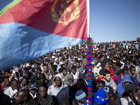 African migrants hold an Eritrean flag during a protest demanding to be recognized as refugees, outside Israel's parliament in Jerusalem on Jan. 8, 2014. Canada is one of the countries expected to resettle African asylum seekers turned away from Israel, but it remains to be seen whether the Liberal government will be increasing the number of refugees from the area who were already destined to arrive here.