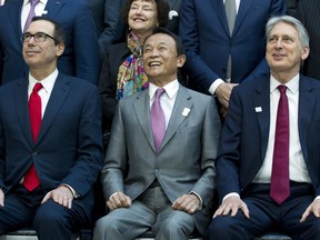 Foreground from left, U.S. Treasury Secretary Steve Mnuchin, Japan's Finance Minister Taro Aso and U.K. Chancellor of the Exchequer Philip Hammond sit with others for the group photo of International Monetary Fund governors at the World Bank/IMF Spring Meetings in Washington, on Saturday, April 21, 2018.