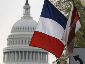 The French flag, along with the American flag and the flag of the District of Columbia, is seen with the U.S. Capitol in the distance in advance of French President Emmanuel Macron's Washington arrival for a state visit, Monday, April 23, 2018. Macron will address Congress this week after meeting with President Donald Trump.