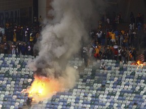 A fire burns in the stands at the Moses Mabhida stedium in Durban, South Africa, Saturday, April 21, 2018, after violence broke out at a soccer game when hundreds of fans ripped up parts of the stadium, invaded the pitch, and assaulted at least one security guard. The incident occurred after the Kaizer Chiefs lost 2-0 to Free State Stars in the semifinals of the Nedbank Cup competition.