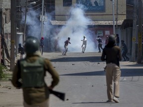 Kashmiri protesters engulfed in tear gas smoke clash with Indian paramilitary soldiers during a protest against the killing of rebels in Srinagar, Indian controlled Kashmir, Sunday, April 1, 2018.