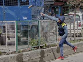 A Kashmiri protester throws stone at an Indian police vehicle during a protest against the killing of civilians in Srinagar, Indian controlled Kashmir, Wednesday, April 11, 2018. Three men were killed in Kashmir when government forces fired on anti-India protesters who thronged a village following a gunbattle that killed three rebels and a soldier, officials said Wednesday.