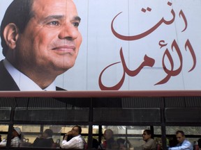 People travel on a public bus under an election banner for Egyptian President Abdel-Fattah el-Sissi with Arabic that reads, "you are the hope," in Cairo, Egypt, Wednesday, March 28, 2018. (