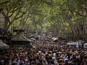 People crowd along the historic Las Ramblas promenade of Barcelona to buy books and roses at makeshift stands as Catalans celebrate the day of their patron saint, Spain, Monday, April 23, 2018. One of the most important holidays in Catalan culture, the day of Sant Jordi or Saint George in English, coincides with World Book Day. To mark the date, lovers close friends and family traditionally gift each other with a red rose and a book. But many Catalans this year are using the holiday to make a political statement.