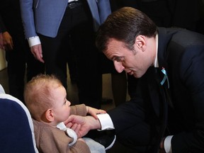 French President Emmanuel Macron talks to a baby as he visits the Rouen hospital, Normandy, Thursday, April 5, 2018. French President Emmanuel Macron is unveiling a long-awaited autism plan for a country that is shockingly behind the curve on providing basic education and care for people on the autism spectrum.