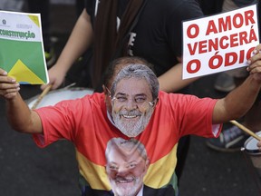 A demonstrator wearing a mask of former Brazil's President Luiz Inacio Lula da Silva, carries a sign written in Portuguese that reads "Love Will Overcome Hate," right,  and the Brazilian constitution on his right hand, during a protest in support of Brazil's former President Luiz Inacio Lula da Silva, in Brasilia, Brazil, Wednesday, April 4, 2018. Brazil's top court could rule as soon as today whether da Silva can stay out of prison while appealing a corruption conviction, a decision that could radically alter October's presidential election in Latin America's largest nation.