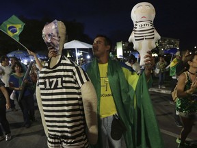 A demonstrator against Brazil's former President Luiz Inacio Lula da Silva holds dolls dressed as an inmate featuring the face of da Silva, outside the National Congress in Brasilia, Brazil, Wednesday, April 4, 2018. Brazil's top court could rule as soon as today whether da Silva can stay out of prison while appealing a corruption conviction, a decision that could radically alter October's presidential election in Latin America's largest nation.