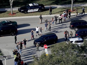 FILE - In this Feb. 14, 2018 file photo, students hold their hands in the air as they are evacuated by police from Marjory Stoneman Douglas High School in Parkland, Fla., after a shooter opened fire on the campus. Newly released reports are providing more details about the law enforcement response to the massacre of 17 people at the high school. The Coral Springs police released reports on Monday, April 16, from several of its officers.