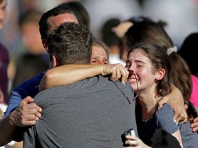 FILE - In this Wednesday, Feb. 14, 2018, file photo, a family reunites following a shooting at Marjory Stoneman Douglas High School in Parkland, Fla. A commission tasked with investigating government actions surrounding the Florida high school massacre and the state's other mass shootings is set to hold its first meeting, Tuesday, April 24.