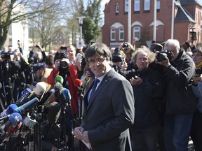 Former Catalan leader Carles Puigdemont, center, gives a press statement after he was released on bail from the prison in Neumuenster, northern Germany, Friday, April 6, 2018.