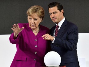German Chancellor Angela Merkel, left, and Mexican President Enrique Pena Nieto chat as they tour the Hannover Messe fair where Mexico is this year's guest country in Hannover, northern Germany, Monday, April 23, 2018.