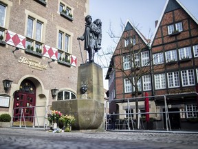 Flowers sit in front of a fountain with the Kiepenkerl, a traditional merchant figure from the Muensterland, in front of the restaurant Kiepenkerl in Muenster, western Germany, Sunday, April 8, 2018, one days after a van crashed into people drinking outside the popular bar, killing two people and injuring 20 others before the driver of the vehicle shot and killed himself inside it.