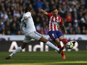 Atletico Madrid's Saul Niguez, right, vies with Real Madrid's Varane during the Spanish La Liga soccer match between Real Madrid and Atletico Madrid at the Santiago Bernabeu stadium in Madrid, Sunday, April 8, 2018. The match ended in a 1-1 draw.
