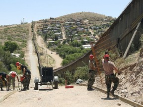 FILE - In this June 20, 2008, file photo, members of the 200th Red Horse Air National Guard Civil Engineering Squadron from Camp Perry in Ohio, including Tech Sgt. David Hughes, right, and Tech Sgt. William Bunker, second from right, work on building a road at the border in Nogales, Ariz. National guard contingents in U.S. states that border Mexico say they are waiting for guidance from Washington to determine what they will do following President Donald Trump's proclamation directing deployment to fight illegal immigration and drug smuggling. Governors of the border states of Arizona and New Mexico have welcomed deployment of the Guard along the southwest border as a matter of public safety.