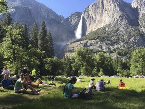 File - In this May 25, 2017 file photo, a class of eighth grade students and their chaperones sit in a meadow at Yosemite National Park, Calif., below Yosemite Falls. Yosemite National Park officials are canceling camping reservations this weekend because of a major storm expected to hit Northern California. Park officials say the warm Pacific storm is expected to have a significant effect on the park and surrounding areas starting Friday, April 6, 2018. Roadways, campgrounds and other facilities could be affected.