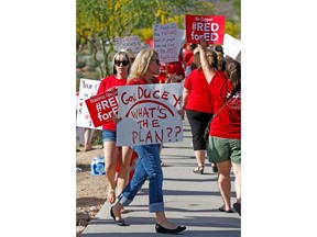 File - In this April 10, 2018, file photo, Arizona teachers march in protest of their low pay and school funding in front of a local radio station waiting for Republican Gov. Doug Ducey to show up for a live broadcast in Phoenix. Arizona Gov. Ducey is pushing lawmakers to approve his proposal for big teacher raises Monday, April 23, 2018, as school districts make plans to shut down if educators statewide walk off the job as planned this week after calling the Republican governor's plan insufficient.