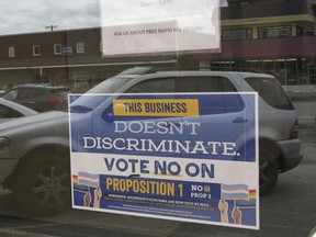 In this photo taken Monday, April 9, 2018, is a sign on a business door urging defeat of a proposition that would have rolled back protections for transgender residents in Anchorage, Alaska. Residents of Anchorage, Alaska's largest city, became the first voters in the nation to reject a so-called bathroom bill at the ballot.