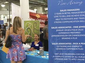 In this Jan. 31, 2018 photo, a woman speaks to Maui Divers Jewelry representatives at a job fair in Honolulu. Recently released numbers show Hawaii boasts the United States' lowest jobless rate, at 2.1 percent. But experts say the figure is masking underlying problems.