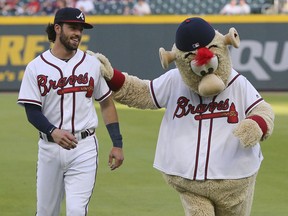 Atlanta Braves shortstop Dansby Swanson jokes around with team mascot Blooper while preparing to play the Philadelphia Phillies in a baseball game on Tuesday, April 17, 2018, in Atlanta.