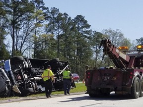 Police officers and emergency workers examine the scene of the accident scene Thursday morning, April 5, 2018, after a tour bus heading to the Masters golf tournament overturned along Interstate 20 near Augusta, Ga. Authorities say at least a dozen people were injured and the bus driver Steven Hoppenbrouwer was charged with DUI.