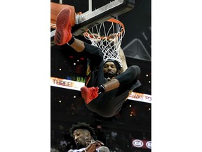 Atlanta Hawks forward DeAndre' Bembry hangs from the basket after dunking on Philadelphia 76ers forward Robert Covington, below him, during the first half of an NBA basketball game Tuesday, April 10, 2018, in Atlanta.