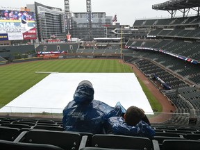 Atlanta Braves fans look out over the covered infield as they wait for the start of a baseball game against the New York Mets Sunday, April 22, 2018, in Atlanta.