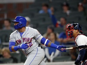 New York Mets' Yoenis Cespedes (52) drives in the go-ahead run with a single in front of Atlanta Braves catcher Kurt Suzuki during the 12th inning of a baseball game Friday, April 20, 2018, in Atlanta. New York won 5-3 in 12 innings.