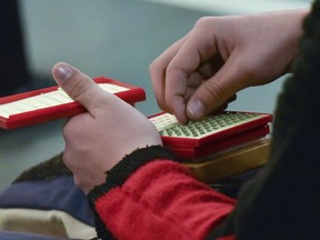 In this photo taken Saturday, March 17, 2018, in Dahlonega, Georgia, a student holds a container of pellets used in an air rifle during training at a gun range at the University of North Georgia. In the wake of the shooting at a high school in Parkland, Florida, some Americans are questioning whether school gun clubs are wise. But those who participate, say it teaches them discipline, patience and life skills.