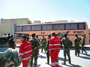 This photo released by the Syrian official news agency SANA, shows Syrian government forces overseeing the evacuation of Army of Islam fighters and their families in buses, from the besieged town of Douma, just east of Damascus, Syria, Monday, April 2, 2018. The most powerful Syrian rebel faction on the fringes of Damascus began abandoning its stronghold in the once rebel-held enclave of eastern Ghouta on Monday, opening the way for government forces to secure full control of the area, after seven years of revolt. (SANA via AP)