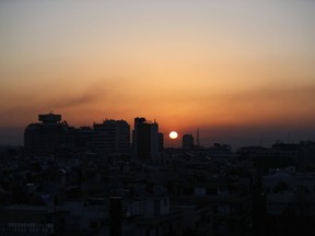 CORRECTS TO SUNRISE - Smoke rises at sunrise after airstrikes targeting different parts of the Syrian capital Damascus, early Saturday, April 14, 2018. Syria's capital has been rocked by loud explosions that lit up the sky with heavy smoke as U.S. President Donald Trump announced airstrikes in retaliation for the country's alleged use of chemical weapons.
